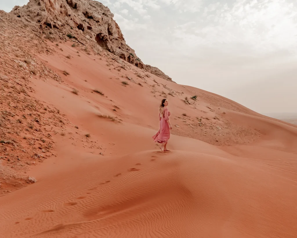 Ida Eriksson walking in the Sharjah desert, United Arab Emirates, surrounded by orange sand dunes.