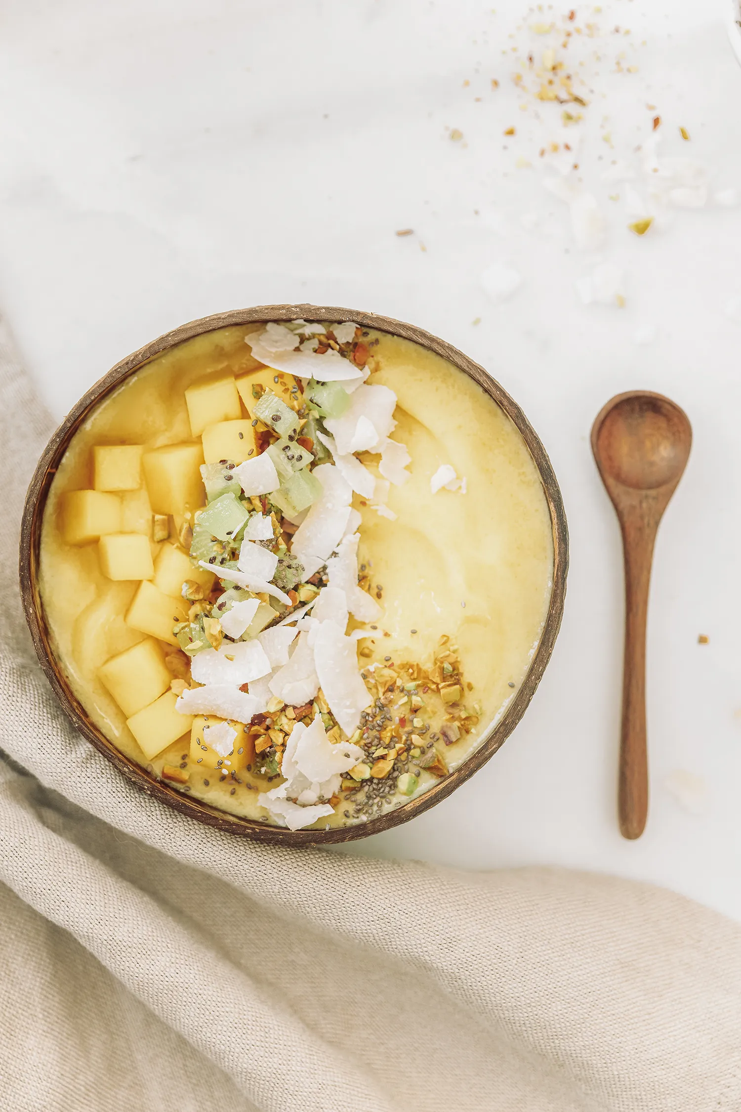 Vegan recipe for a mango pineapple smoothie bowl including frozen mango, pineapple, banana and coconut milk.
