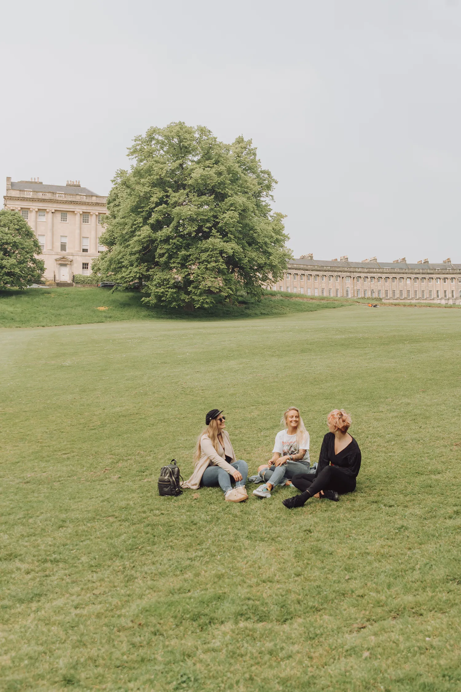 Travel bloggers sitting on the lawn in front of the Royal Crescent in Bath, England.
