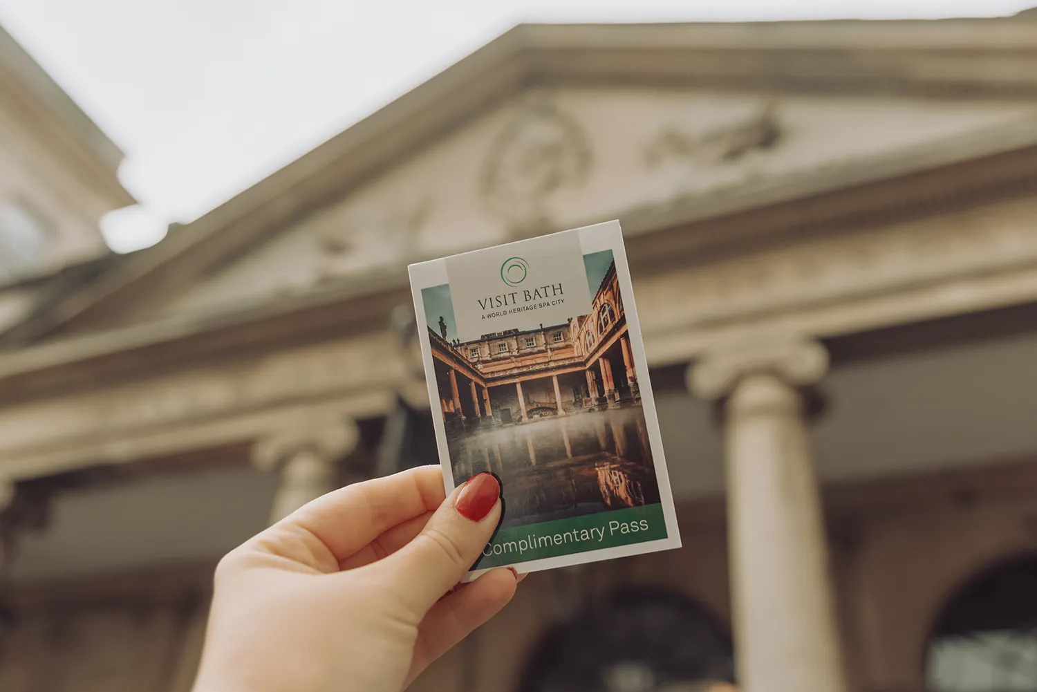 Entrance ticket to the Roman Baths in Bath, England, held in front of the historic building.