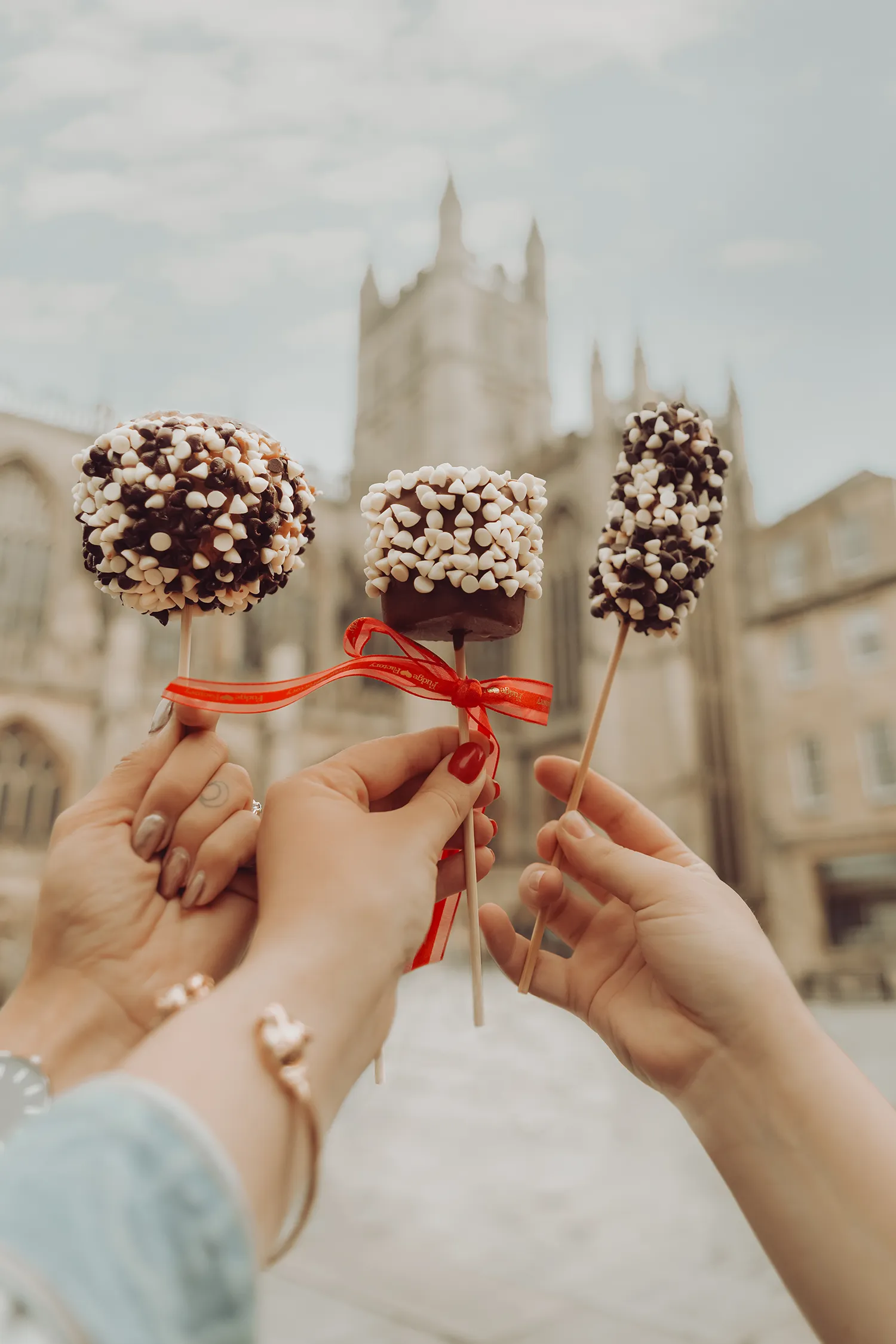 Chocolate fudge treats from San Francisco Fudge Factory in Bath, England, held up in front of Bath Abbey.
